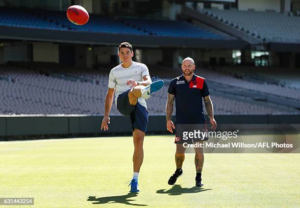 Canadian tennis player Milos Raonic and Melbourne AFL captain Nathan Jones kick the football during a Melbourne Demons AFL media opportunity at...