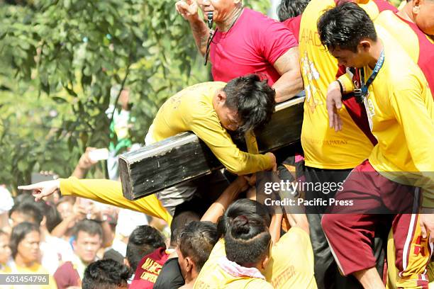 Devotee hangs limply across the cross of the Black Nazarene out of exhaustion after successfully touching the miraculous Icon. Devotees observe this...