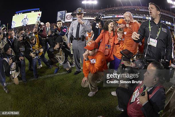 Playoff National Championship: Clemson coach Dabo Swinney victorious down on one knee with wife Kathleen after winning game vs Alabama at Raymond...