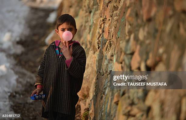 An Kashmiri boy blows a bubble as he chews gum in a neighbourhood on the outskirts of Srinagar following the season's first snowfall in Kashmir on...