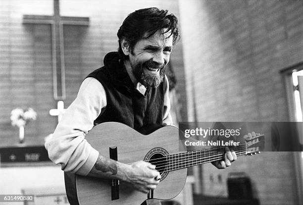 The Inmate Nation: Portrait of Charles Manson playing guitar in chapel during photo shoot at California Medical Facility. Vacaville, CA 7/1/1982 -...