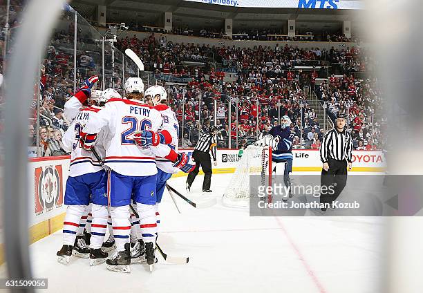 Goaltender Connor Hellebuyck of the Winnipeg Jets looks on as Montreal Canadiens players celebrate a first period goal by Brian Flynn at the MTS...