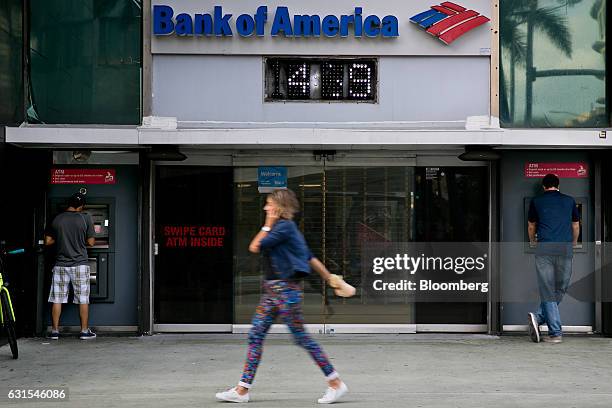 Pedestrian talks on a mobile device as customers use automatic teller machines outside a Bank of America Corp. Branch in Miami Beach, Florida, U.S.,...