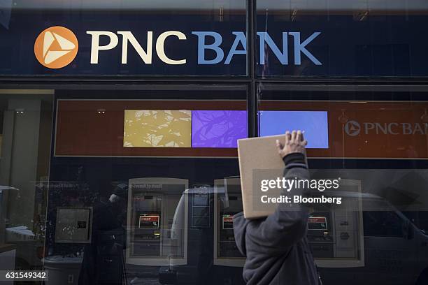 Pedestrian carries a box while passing in front of PNC Financial Services Group Inc. Bank branch in New York, U.S., on Monday, Jan. 9, 2017. PNC...