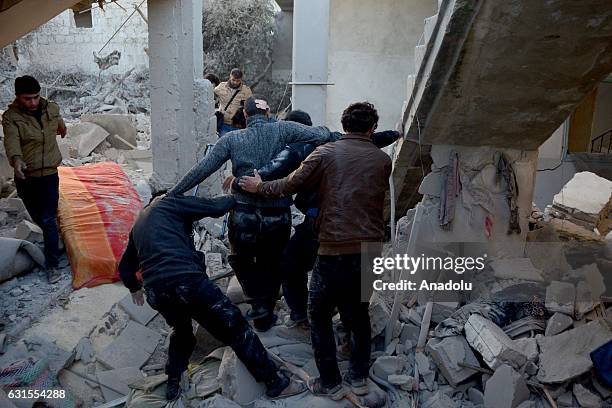 Civilians and search and rescue team members pull a man out of the debris after a warcraft belonging to Syrian army hit Binnish town of Idlib in...