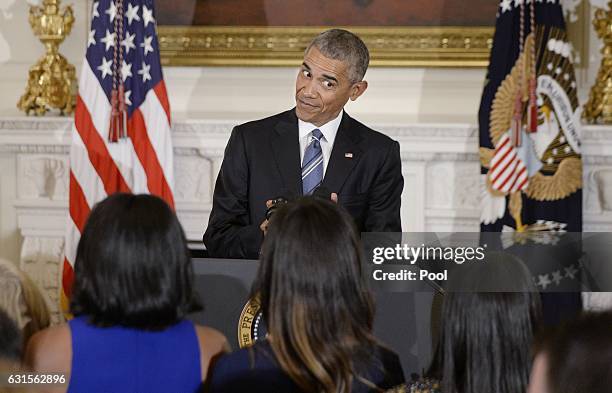 President Barack Obama looks at his wife Michelle and his daughters Malia and Sasha during an event in the State Dining room of the White House,...