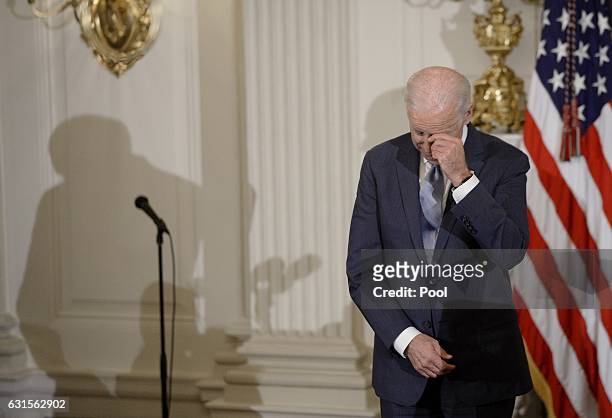 Vice President Joe Biden wipes his eyes as Preident Barack Obama presents him with Medal of Freedom during an event in the State Dining room of the...