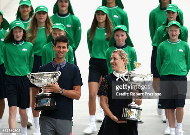 Defending champions Novak Djokovic of Serbia and Angelique Kerber of Germany carry the Australian Open trophies prior to the official draw ahead of...