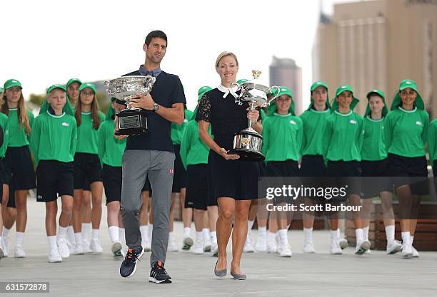Australian Open winners Novak Djokovic of Serbia and Angelique Kerber of Germany pose with their winners trophies as ball kids follow them during the...