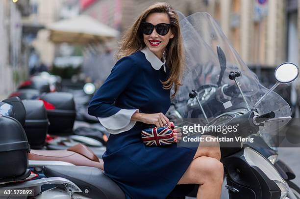 German fashion blogger and model Alexandra Lapp sitting on an Italian vespa is wearing navy blue knee-length shirt dress in flared cut with removable...