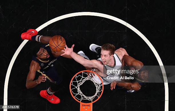 Justin Hamilton of the Brooklyn Nets leaps for a rebound with Tyreke Evans and E'Twaun Moore of the New Orleans Pelicans during their game at the...