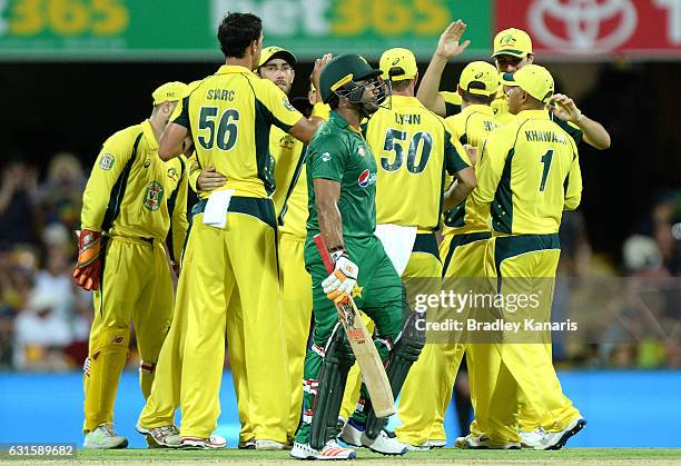 Umar Akmal of Pakistan looks dejected after losing his wicket as the Australian team celebrate during game one of the One Day International series...