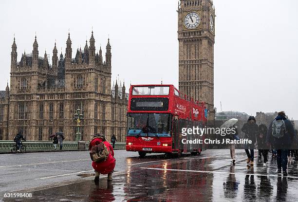 An open top bus drives over Westminster bridge as snow falls on January 13, 2017 in London, United Kingdom. The Met Office has issued a yellow 'be...