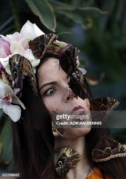 Jessie May Smart, wearing a floral crown made of tropical flowers, reacts as butterflies are placed on her face during a photocall to mark the...