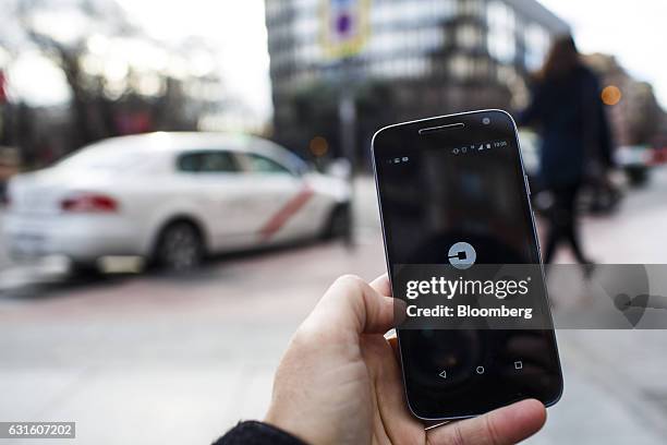 The Uber Technologies Inc. Ride-hailing service smartphone app sits on a smartphone display in this arranged photograph at a taxi rank in Madrid,...