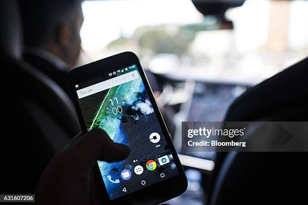 The Uber Technologies Inc. Ride-hailing service app sits on a smartphone screen in the rear of an Uber Technologies Tesla Motors Inc. Model S...