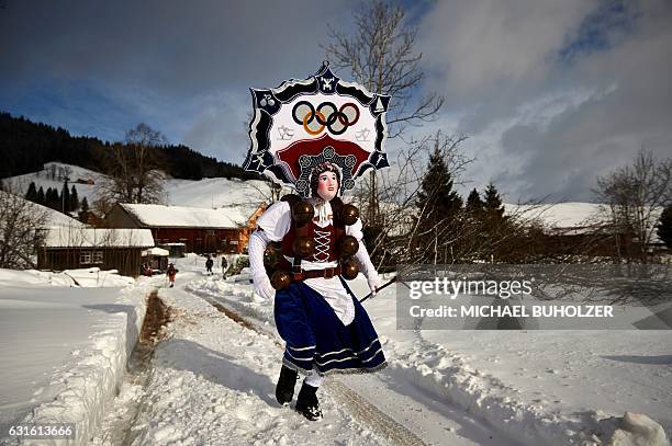 Leader 'Rolli' of a yodel group 'Schuppel' runs in the snow in front of a farmstead during the 'Silvesterchlausen' in the early morning in Urnaesch...