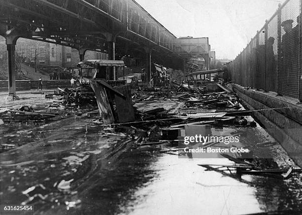 Smashed vehicles and debris sit in a puddle of molasses on Commercial Street on Jan. 16 the day after a giant tank in the North End collapsed,...