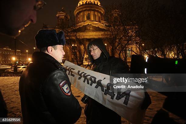 Protester holds a banner as a security member looks at him during a demonstration to protest against the transfer the St. Isaac's Cathedral in St...