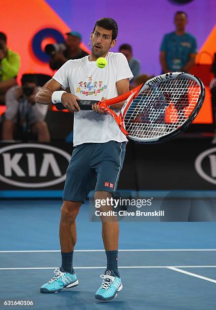 Novak Djokovic of Serbia plays with an oversized tennis racket during kids tennis day exhibition ahead of the 2017 Australian Open at Melbourne Park...