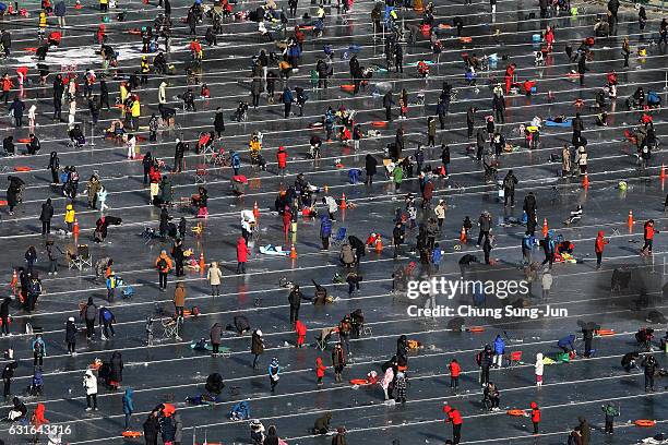 Anglers cast lines through holes into a frozen river during the Hwacheon Sancheoneo or Mountain Trout Ice Festival on January 14, 2017 in...