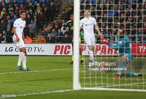 Arsenal's Nigerian striker Alex Iwobi watches a his shot, ricocheted off Swansea City's English defender Kyle Naughton and past Swansea City's Polish...