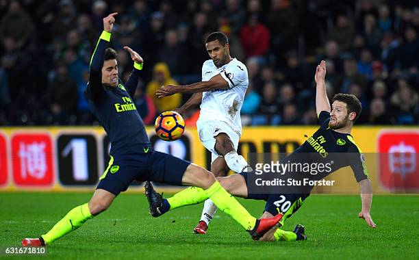 Wayne Routledge of Swansea City shoots, while Gabriel of Arsenal and Shkodran Mustafi of Arsenal block during the Premier League match between...
