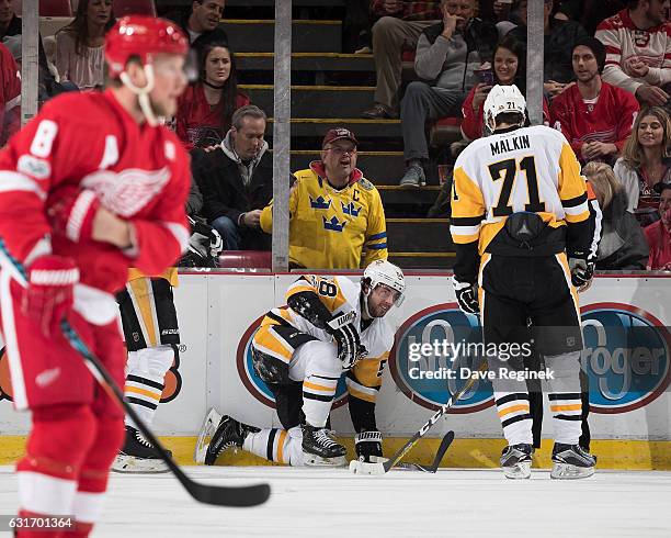 Kris Letang of the Pittsburgh Penguins kneels on the ice after a first period injury while teammate Evgeni Malkin looks over and Justin Abdelkader of...