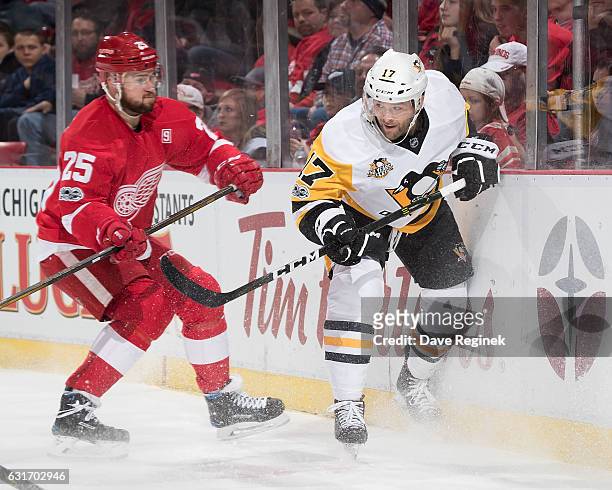 Mike Green of the Detroit Red Wings battles along the boards with Bryan Rust of the Pittsburgh Penguins during an NHL game at Joe Louis Arena on...