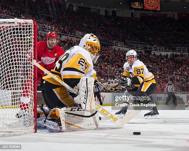 Marc-Andre Fleury of the Pittsburgh Penguins makes a save as teammate Sidney Crosby defends against Drew Miller of the Detroit Red Wings during an...