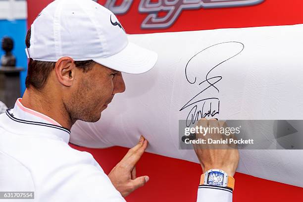 Rafael Nadal of Spain signs the oversized raquet during a Kia Key handover ceremony at Garden Square in Melbourne Park January 15, 2017 in Melbourne,...