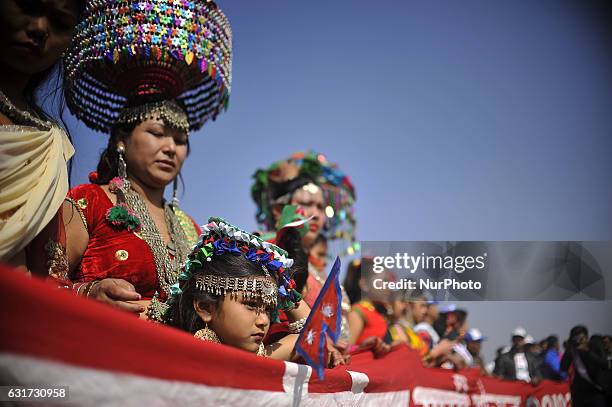 Little Nepalese Tharu community girl in a traditional attire hold national flag of Nepal during prade of the Maghi festival celebrations, or the New...