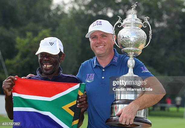 Graeme Storm of England poses with his caddie Jeffrey Wkonyane on the 18th green after beating Rory McIlroy of Northern Ireland in the third play off...