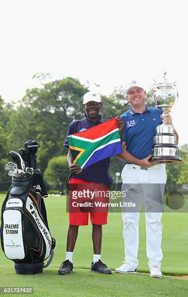 Graeme Storm of England poses with his caddie Jeffrey Wkonyane on the 18th green after beating Rory McIlroy of Northern Ireland in the third play off...