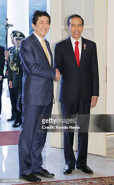 Japanese Prime Minister Shinzo Abe and Indonesian President Joko "Jokowi" Widodo shake hands before their talks at Bogor Palace, south of Jakarta, on...