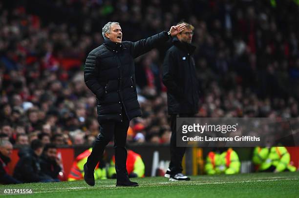Jurgen Klopp manager of Liverpool looks on as Jose Mourinho manager of Manchester United gives instructions during the Premier League match between...