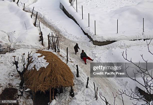 Kashmiri children playing sledges on slippery roads covered with snow at Tangmarg area in Indian Controlled Kashmir on Sunday, January 15, 2017. Cold...