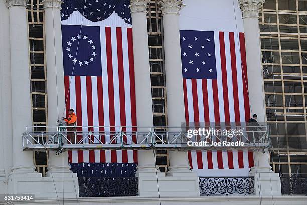 Workers hang flags on the U.S. Capitol to be used as part of the backdrop to the presidential inauguration for President elect Donald Trump as he...