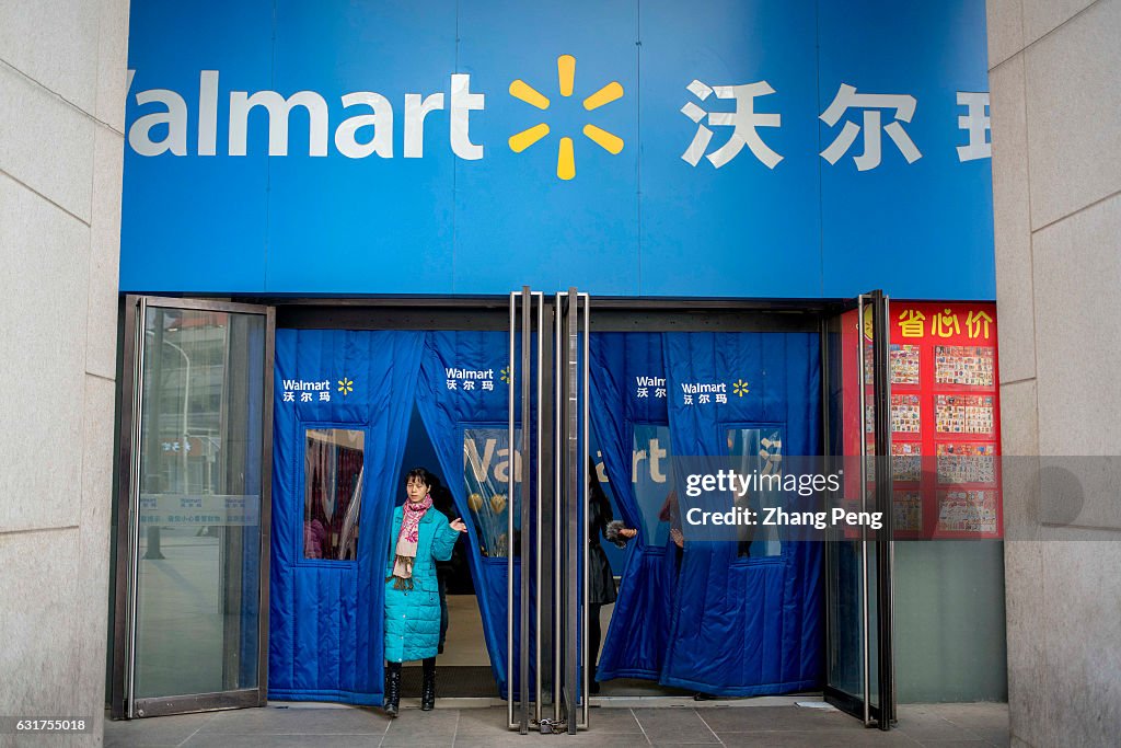 A customer walks out of a Walmart store.  Walmart is about...