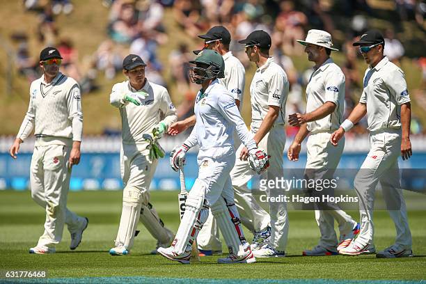 Imrul Kayes of Bangladesh and members of the New Zealand squad leave the field at the end of the Bangladesh innings during day five of the First Test...