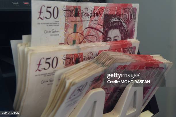 Counting machine tallies British pound notes at a currency exchange in Kuala Lumpur on January 16, 2017. - The pound struggled at 32-year lows...