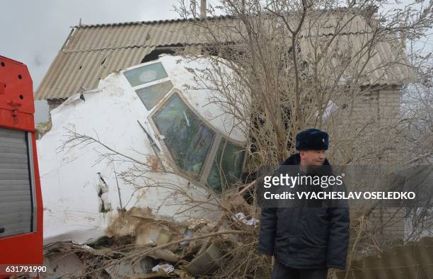 Police officer stands by the wreckage of a Turkish cargo plane at the crash site in the village of Dacha-Suu outside Bishkek on January 16, 2017. A...