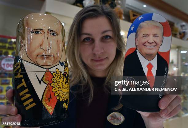 An employee displays traditional Russian wooden nesting dolls, Matryoshka dolls, depicting US President-elect Donald Trump and Russian President...