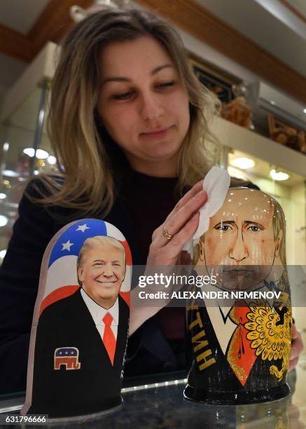 An employee polishes traditional Russian wooden nesting dolls, Matryoshka dolls, depicting US President-elect Donald Trump and Russian President...