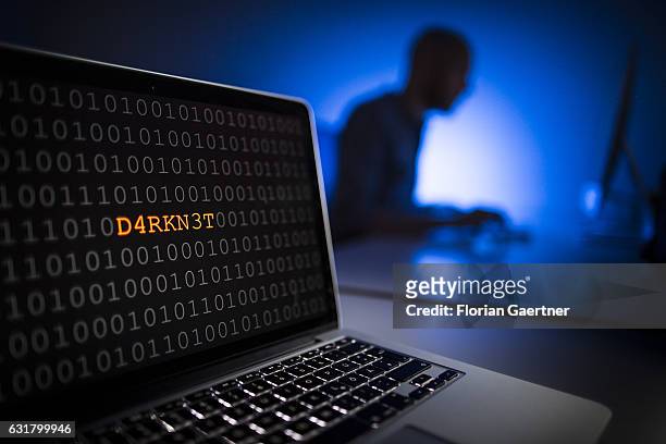 Illustration about 'Darknet'. Closeup of a laptop with binary code. In the background, a man sits on a computer on January 13, 2017 in Berlin,...