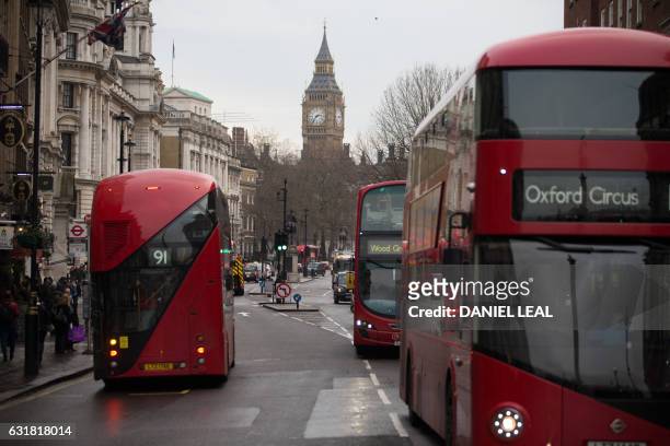 Red double-decker buses pass along Whitehall with the Big Ben clock face and the Elizabeth Tower behind, in central London on January 16, 2017. -...