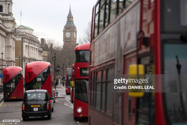 Red double-decker buses pass along Whitehall with the Big Ben clock face and the Elizabeth Tower behind, in central London on January 16, 2017. -...
