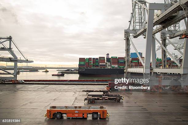 Automated guided vehicles stand beside gantry cranes on the dockside at the Delta Terminal, operated by Europe Container Terminals BV , at the Port...