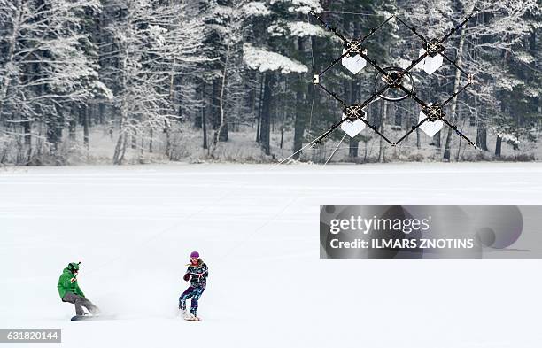 Snowboarders are pulled by sixteen propeller drone on Niniera lake surface near Cesis, Latvia, on January 14, 2017. / AFP / afp / Ilmars ZNOTINS