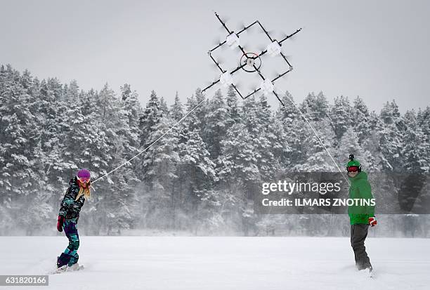 Snowboarders are pulled by sixteen propeller drone on Niniera lake surface near Cesis, Latvia, on January 14, 2017. / AFP / afp / Ilmars ZNOTINS